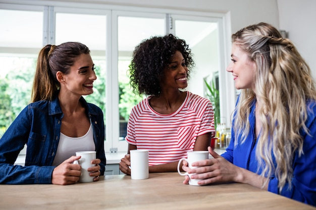 Amigas con taza de café sentado en la mesa