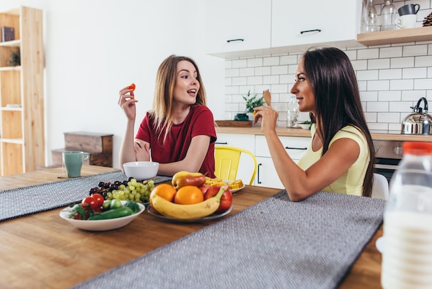 Amigas tomando frutas en el desayuno en la cocina.