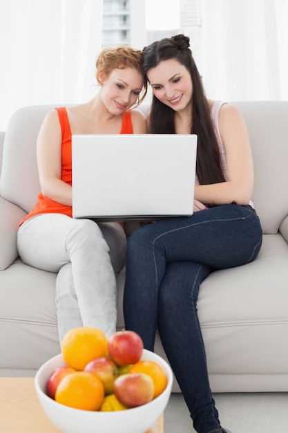 Amigas usando laptop juntos en casa