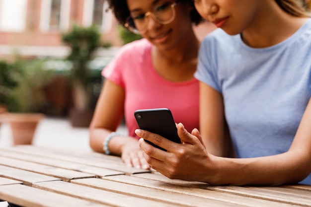 Amigas usando o telefone enquanto estão sentadas à mesa