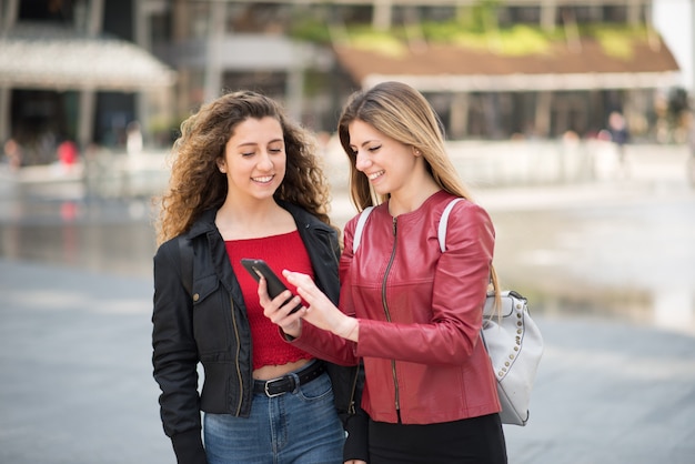 Amigas usando su teléfono móvil juntos