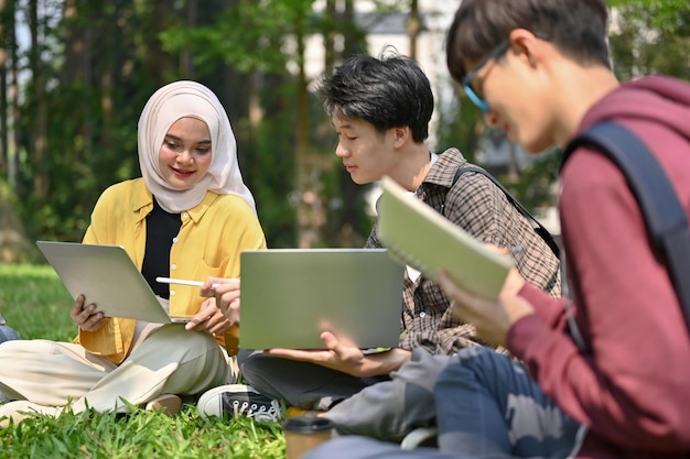 Amigável estudante universitária muçulmana asiática conversando com seu amigo no parque