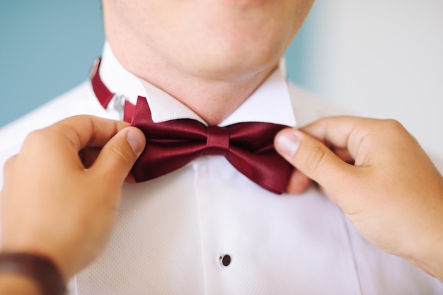 Amigo ajudando o noivo enquanto usa gravata de papagaio durante o casamento