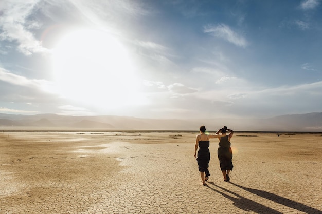 Foto amigos a caminhar no deserto contra o céu durante o dia ensolarado