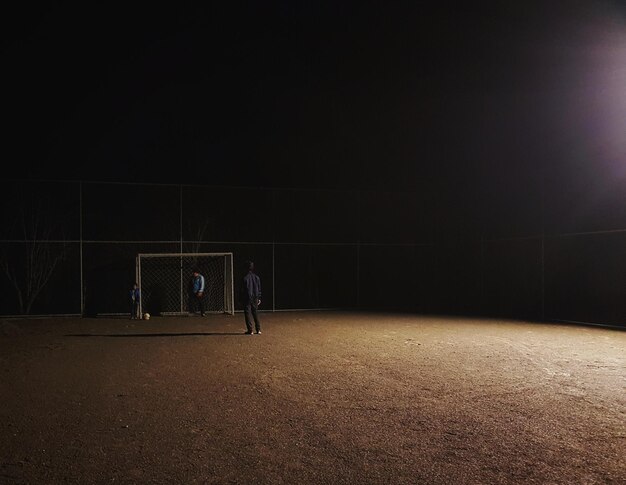 Foto amigos a jogar futebol à noite.