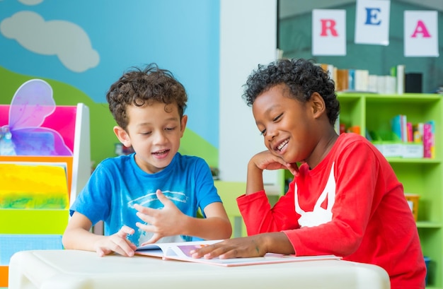 Foto amigos a ler um livro na mesa na pré-escola