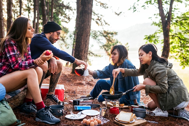 Amigos acampando comiendo comida concepto