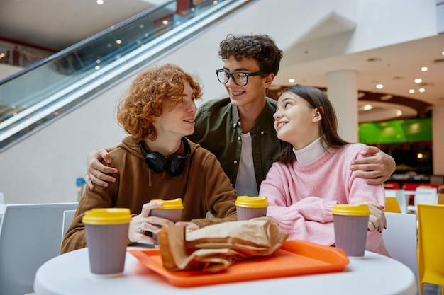 Foto amigos adolescentes comendo um lanche durante uma caminhada no centro comercial