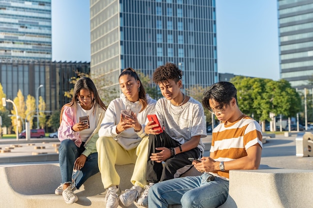 Amigos adolescentes felices multirraciales mirando el teléfono y riendo en el campus