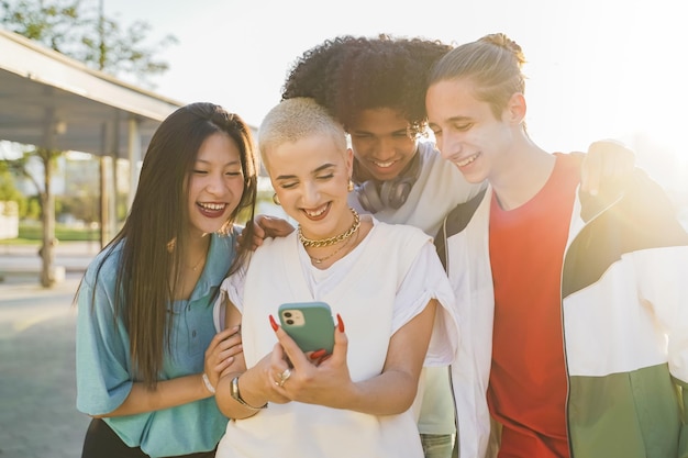 Amigos adolescentes multiétnicas olhando para o telefone e rindo felizes no campus