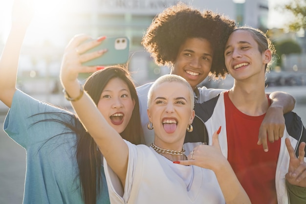 Amigos adolescentes multiétnicos tomando una foto de grupo selfie y riendo felices en el campus Tecnología