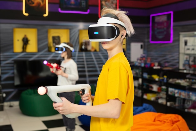 Amigos adolescentes, un niño y una niña con un casco de realidad virtual con gafas y movimiento manual