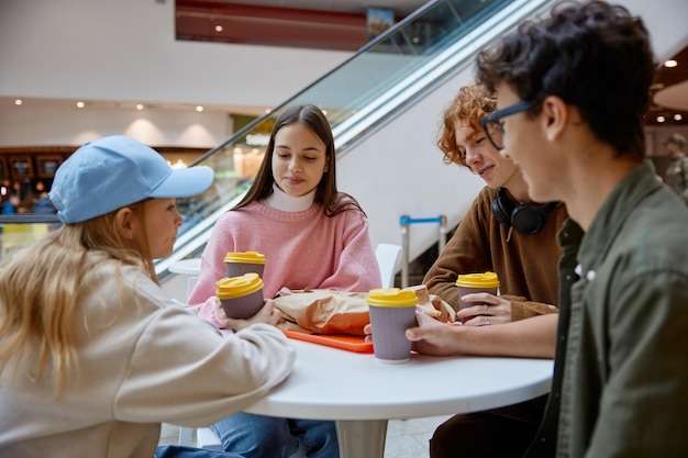 Amigos adolescentes tomando un bocadillo durante una caminata en el centro comercial
