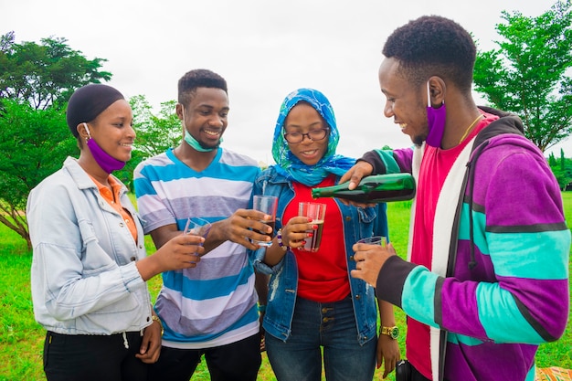 Amigos africanos felizes transformando a bebida em seu copo - conceito de amizade