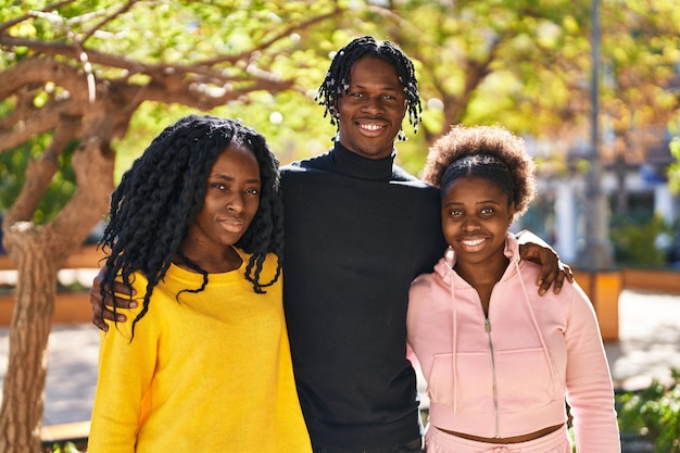 Amigos afroamericanos sonriendo confiados abrazándose unos a otros en el parque