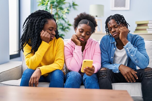 Amigos afroamericanos usando un teléfono inteligente sentado en un sofá en casa