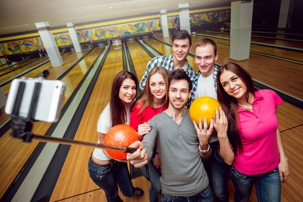 Amigos alegres en la bolera con las bolas.