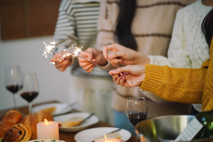 Foto amigos alegres disfrutando de la fiesta de cumpleaños en casa los amigos asiáticos sostienen luces con sparkler celebrando la navidad o la fiesta de nochevieja
