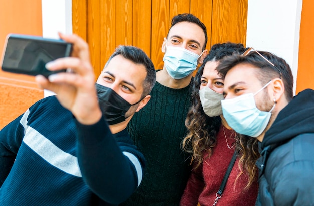 Foto amigos alegres haciendo selfies mientras están de pie contra una pared de madera