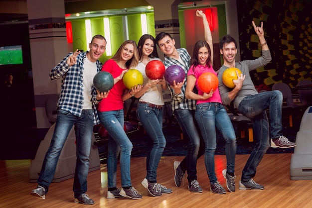 Amigos alegres no boliche com as bolas.