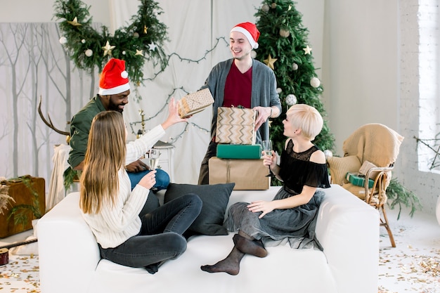 Amigos alegres trocando presentes na véspera de Natal