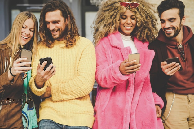 Amigos alegres usando el teléfono móvil al aire libre