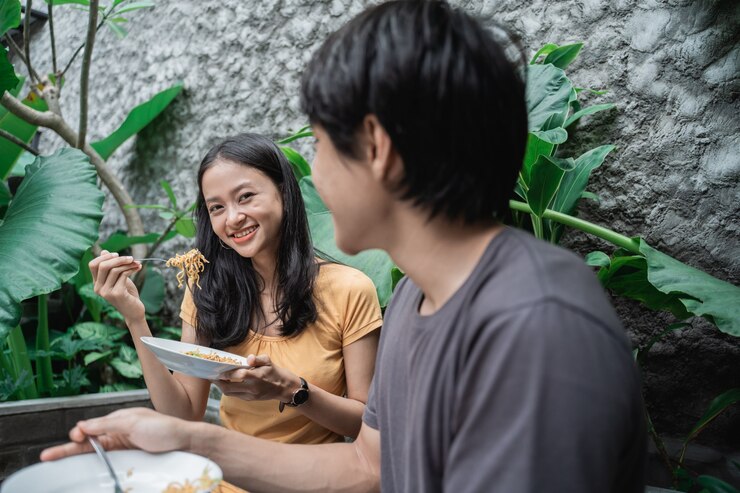 Foto amigos almoçando na natureza comendo macarrão. casal se divertindo comendo e bebendo em um piquenique
