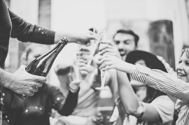 Amigos y amigas alegres brindando con flautas de champán durante una fiesta al aire libre