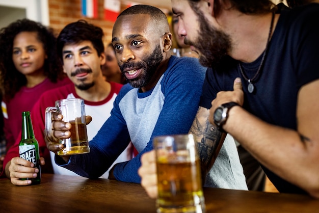 Amigos animando deporte en el bar juntos