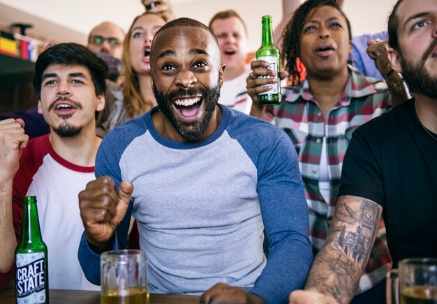 Amigos animando deporte en el bar juntos