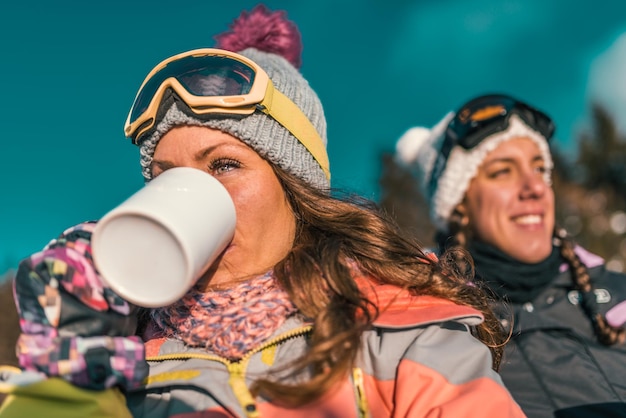 Amigos aproveitando o dia de inverno na montanha tomando café ou chá ao ar livre