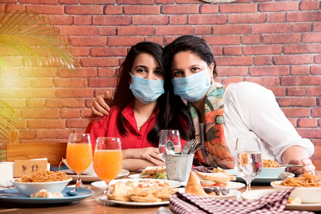 Amigos asiáticos indios comiendo en el restaurante Concepto de comedor con mascarilla protectora después de la pandemia de corona