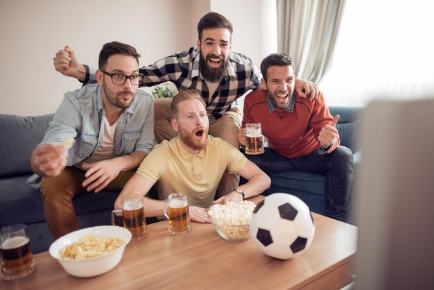 Amigos assistindo jogo de futebol na televisão