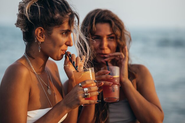 Foto amigos atraentes curtindo férias juntos na praia e bebendo coquetéis