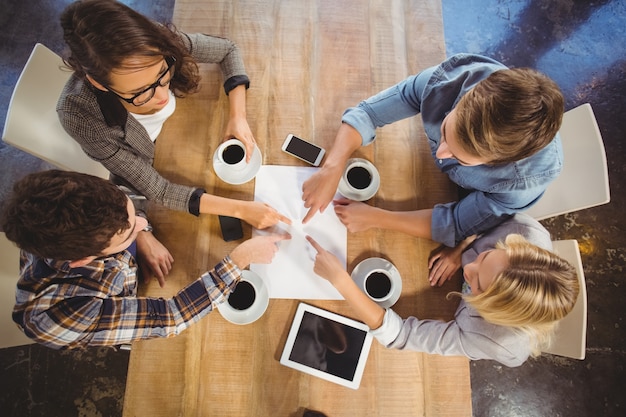 Amigos bebendo café e apontando para papel