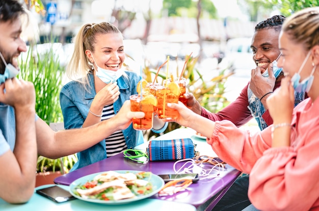 Amigos, bebendo spritz no bar com máscaras