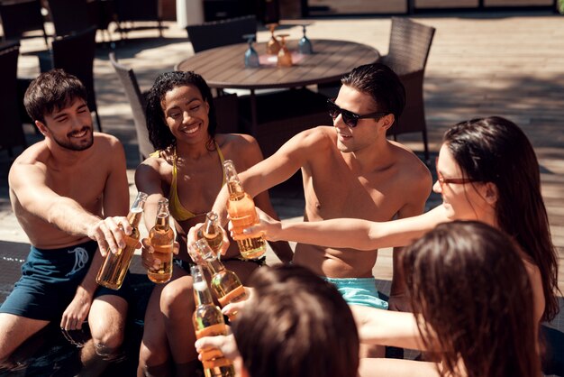 Amigos con bebidas alcohólicas en la piscina