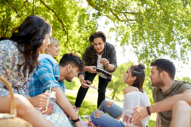 Foto amigos con bebidas y comida en un picnic en el parque