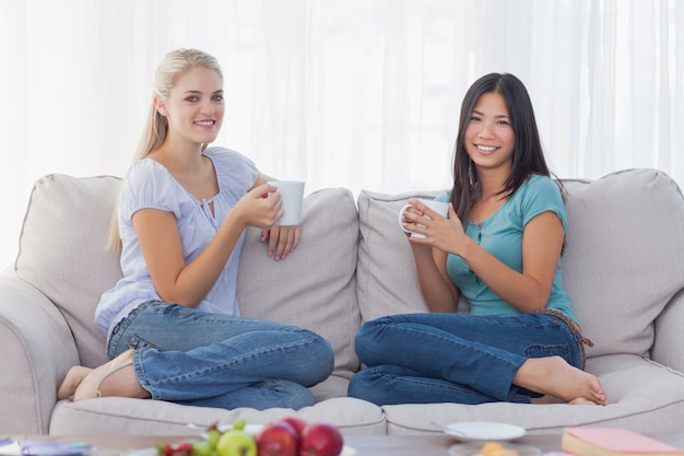 Amigos bebiendo café juntos y sonriendo a la cámara