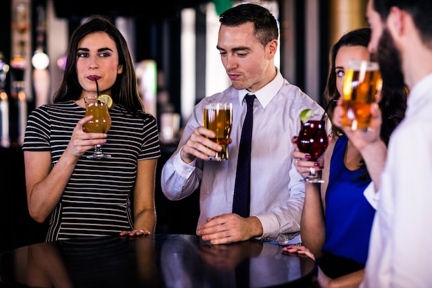 Amigos bebiendo cócteles y cervezas en un bar