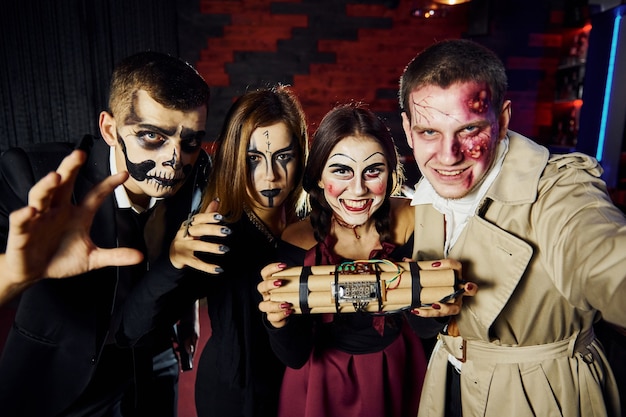 Amigos con bomba en las manos está en la fiesta temática de Halloween con disfraces y maquillaje aterrador.