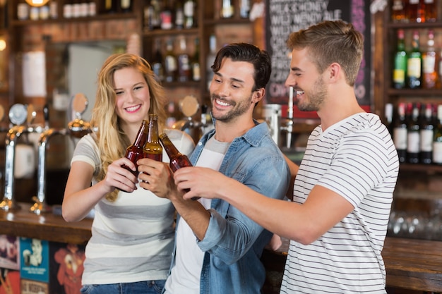 Amigos brindando a garrafas de cerveja no pub