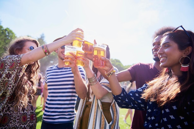 Amigos brindando con bebidas en vasos contra el cielo