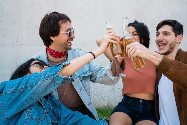 Foto amigos brindando una botella de cerveza contra la pared