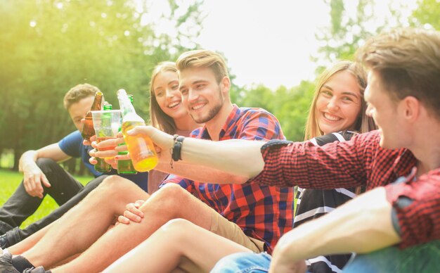 Amigos brindando cerveza en la barbacoa en la naturaleza