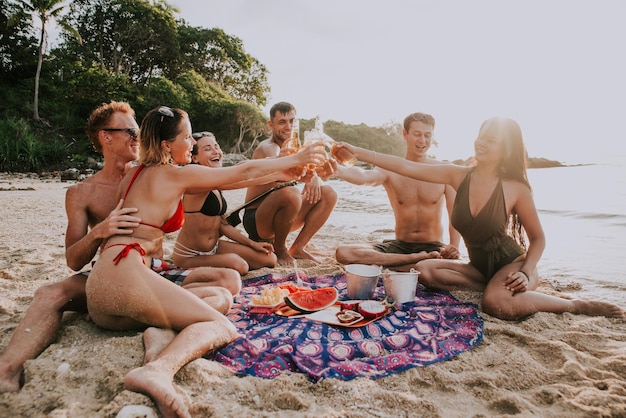 Amigos brindando com garrafas de cerveja enquanto estão sentados na praia