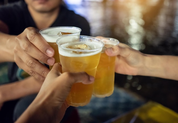 Amigos brindando copas de cerveza en el bar