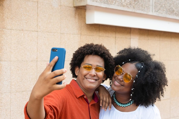 Amigos con cabello afro tomando selfies en la calle de la ciudad