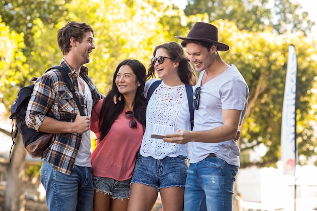 Amigos de la cadera mirando teléfono inteligente en las calles