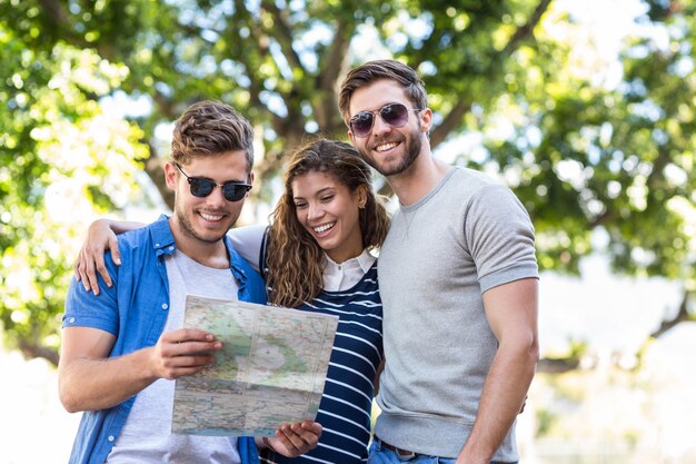 Amigos de cadera revisando el mapa al aire libre y sonriendo